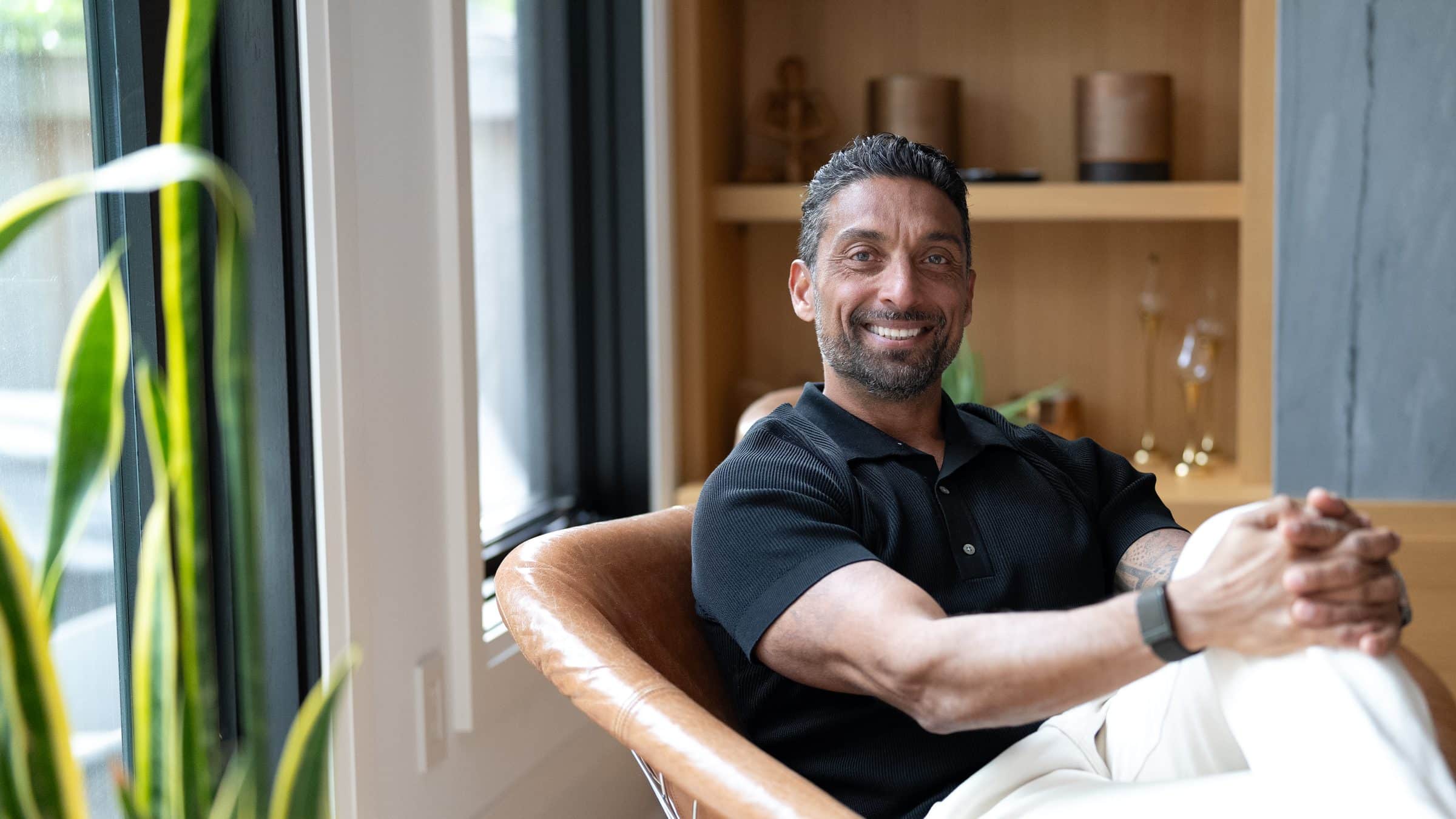 Zarak Fatah smiling, seated in a leather chair at home